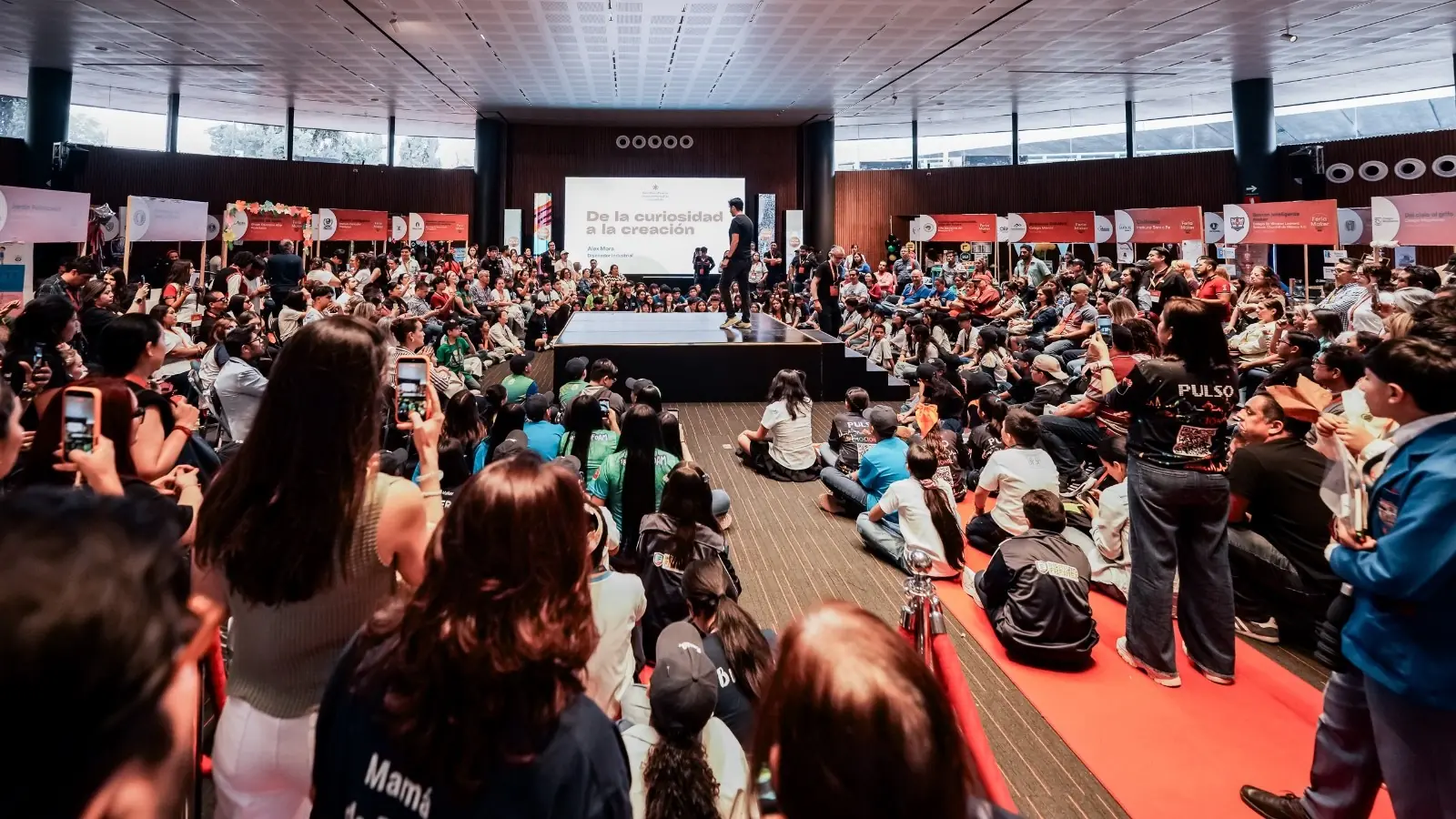 Público de la Feria Maker UNOi sentado alrededor del escenario durante una conferencia